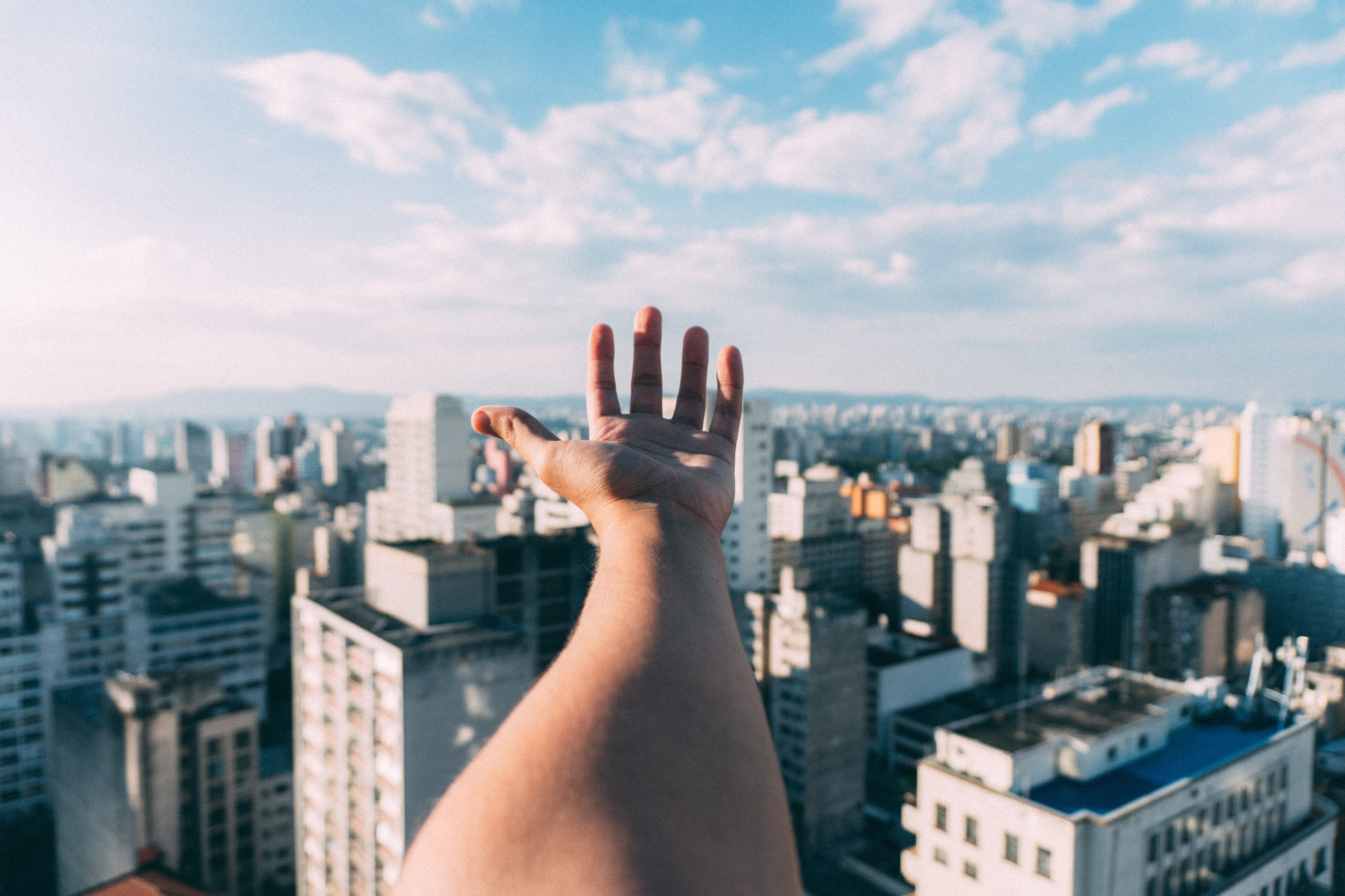 ciudades sostenibles, imagen de una mano por encima de una ciudad con cielo despejado